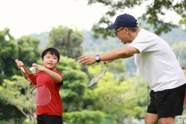 istock Father and son playing badminton in a public park 1405378388