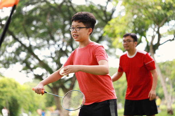 istock Father and son playing badminton in a public park 1405378389