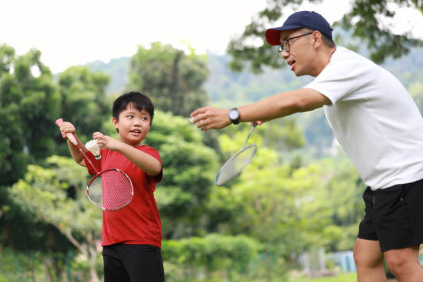 istock Father and son playing badminton in a public park 1405378390