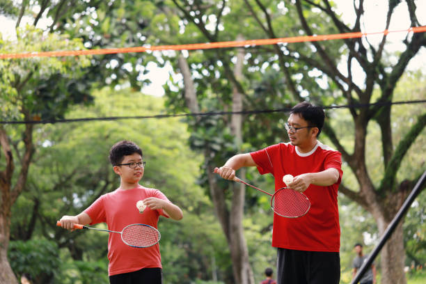 istock Father and son playing badminton in a public park 1405378393