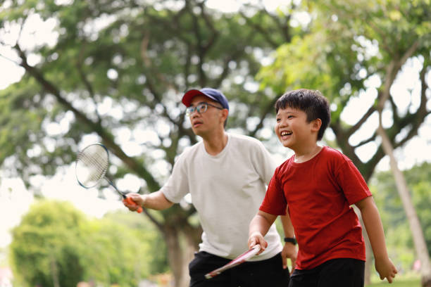 istock Father and son playing badminton in a public park 1405378394