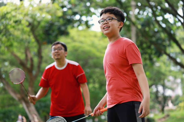 istock Father and son playing badminton in a public park 1405378396
