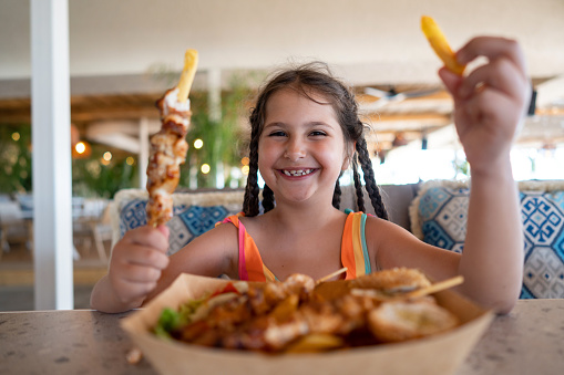 Portrait of Caucasian girl eating souvlaki in the restaurant, during vacation