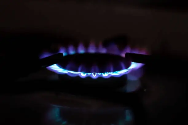 Gas stove burner with blue flames in the dark. Use of gas in home life.