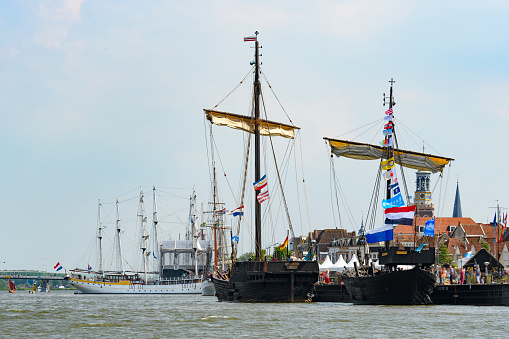 Old traditional sailing ships during the Hanzedagen festival in the Hanseatic League city of Kampen in The Netherlands. The Hanseatic League was a commercial and defensive confederation of merchant guilds and their market towns during the late Middle Ages until the late 19th century. Each year one of the member cities of the New Hansa hosts the Hanseatic Days.  People are watching the ships.