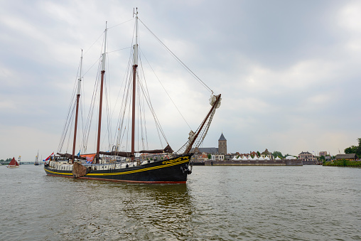 Old traditional sailing ships during the Hanzedagen festival in the Hanseatic League city of Kampen in The Netherlands. The Hanseatic League was a commercial and defensive confederation of merchant guilds and their market towns during the late Middle Ages until the late 19th century. Each year one of the member cities of the New Hansa hosts the Hanseatic Days.  People are watching the ships.