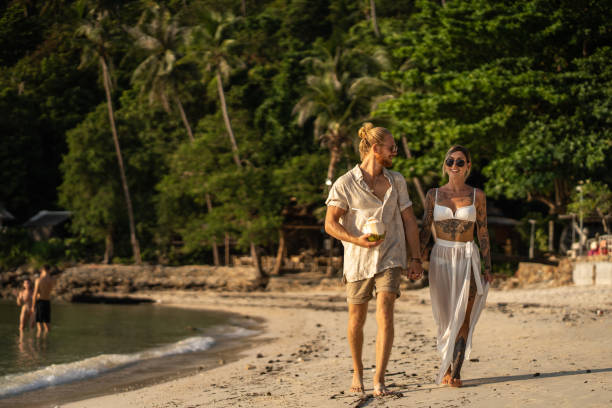 Carefree young couple walking on the beach while holding hands