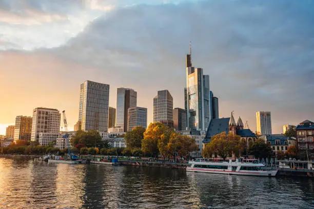 View on Frankfurt financial district skyscrapers over the river Main with tour boats at sunset