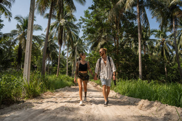 Caucasian couple walking through rainforest Adventurous young Caucasian couple exploring the rainforest tourist couple candid travel stock pictures, royalty-free photos & images