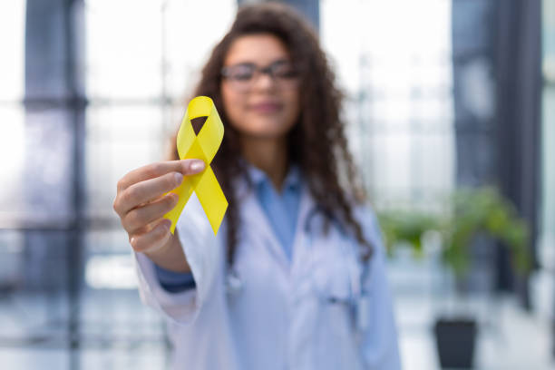 Doctor in a white uniform holds a yellow ribbon in her hand, symbol of the fight against the cat's tumor, problem of suicides and their prevention Doctor in a white uniform holds a yellow ribbon in her hand, symbol of the fight against the cat's tumor, problem of suicides and their prevention. suicide stock pictures, royalty-free photos & images
