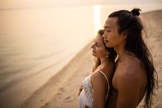 istock Embraced multiracial couple admiring sunset on the beach 1405388210