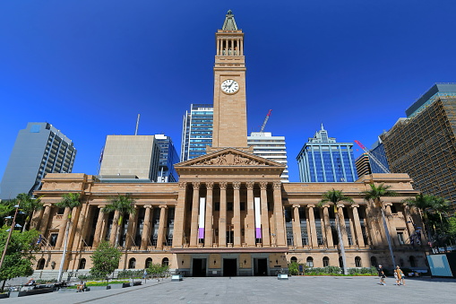 City Hall seen from King George Square-three story building designed in Italian Renaissance style-tall clock tower-sculpted tympanum-Corinthian and Ionic capitel columns. Brisbane-Queensland-Australia. INCIDENTAL PEOPLE IN THE IMAGE.