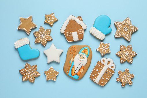 Tasty gingerbread cookies on light blue background, flat lay. St. Nicholas Day celebration