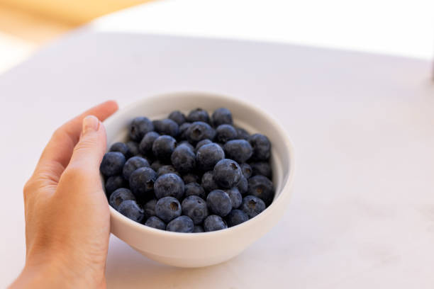 istock Woman's hand holding plate with fresh blueberries. 1405389899