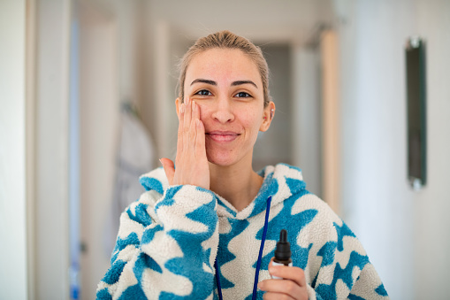 Woman With Acne Applying Against Serum