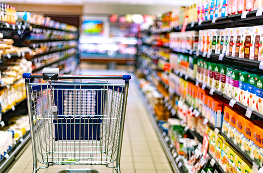 A shopping cart by a store shelf in a supermarket