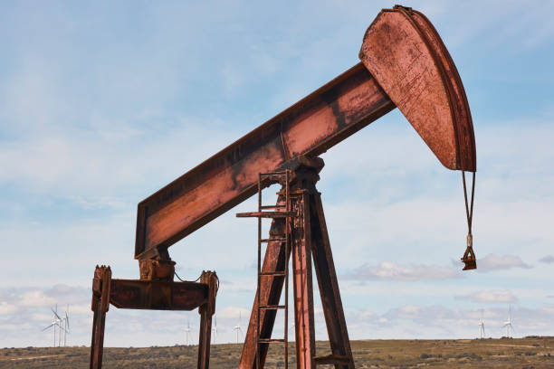 istock Oil pumping machine. Pump jack and windmills. Global warming 1405394481
