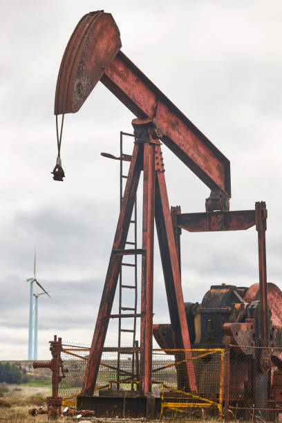 istock Oil pumping machine. Pump jack and windmills. Global warming 1405394522