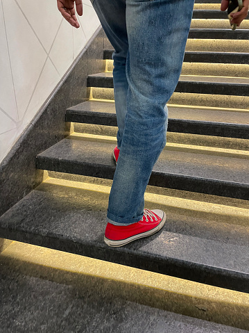Stock photo showing the back view of an unrecognisable man walking up a flight of stairs.