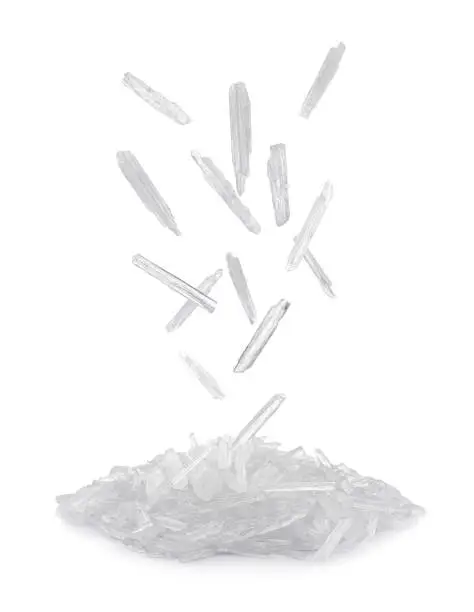 Translucent menthol crystals falling into pile on white background