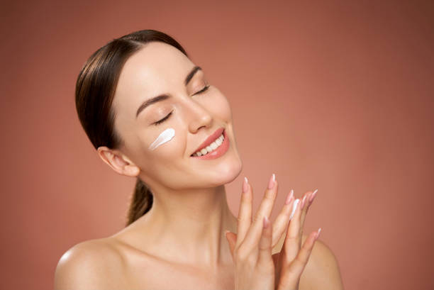 istock Smiling woman applying cream on face 1405398742