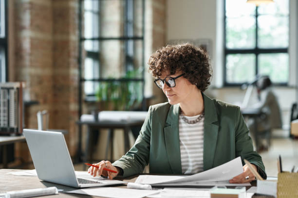 imprenditrice che lavora su laptop in ufficio - architect women blueprint eyewear foto e immagini stock