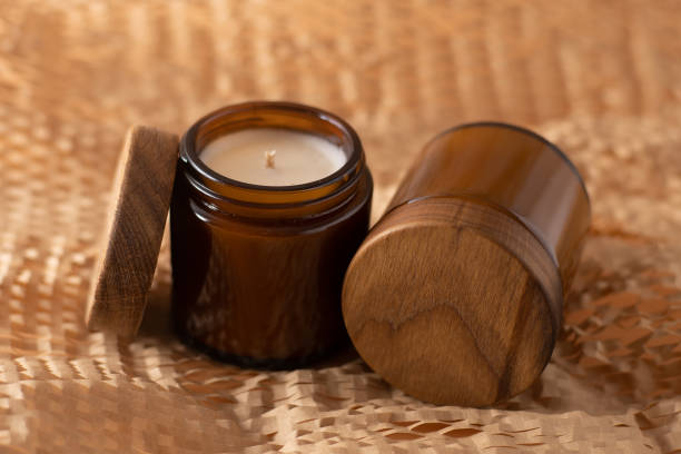 bougies de soja dans un bocal en verre brun avec un couvercle en bois. aromathérapie. bougie sur fond beige. place pour une étiquette. cire et mèche. décoration intérieure. fait main. désodorisant. - bougie ambre photos et images de collection