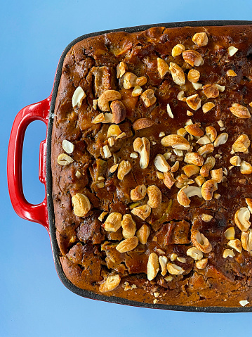 Stock photo showing close-up, elevated view of baking dish of freshly baked carrot and apple cake on a blue background.
