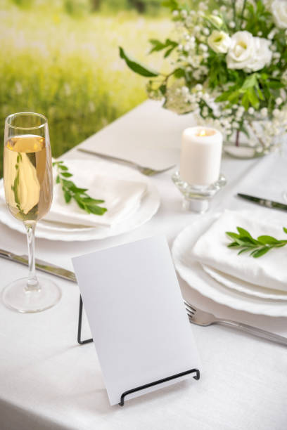 istock Mockup white blank space card for table number or menu. Wedding teble decoration with white flowers, glasses and white napkins. Elegantly decorated table at a wedding reception. Festive table setting. The wedding decor. 1405406575