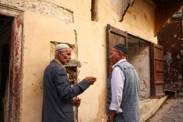 Fez, Morocco-September 23, 2013: Two old men talking in an old street in Fez. Both are wearing skullcaps and their backs are turned.