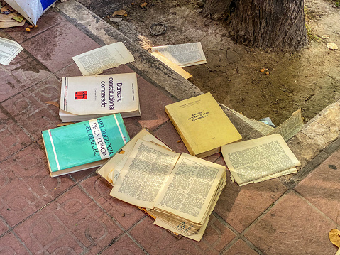 Valencia, Spain - June 10, 2022: High angle view of several economics and law books thrown in the street. Old editions of books become outdated and people even don't want to pass them away and rather prefer to dispose of them