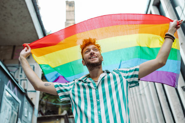 istock Young gay man holding rainbow flag and walking 1405409077