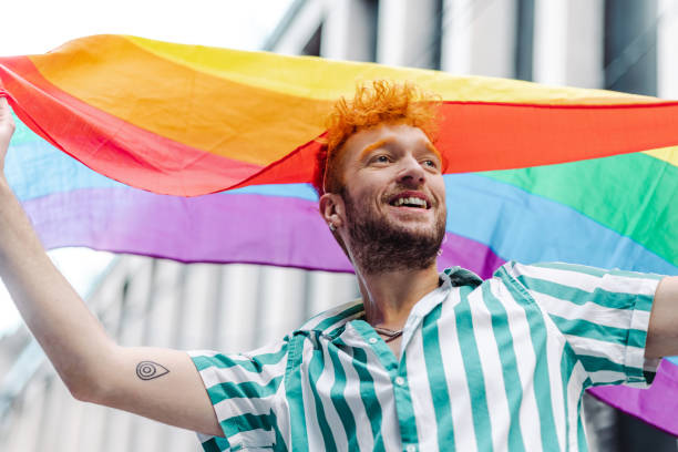istock Young gay man holding rainbow flag and walking 1405409413