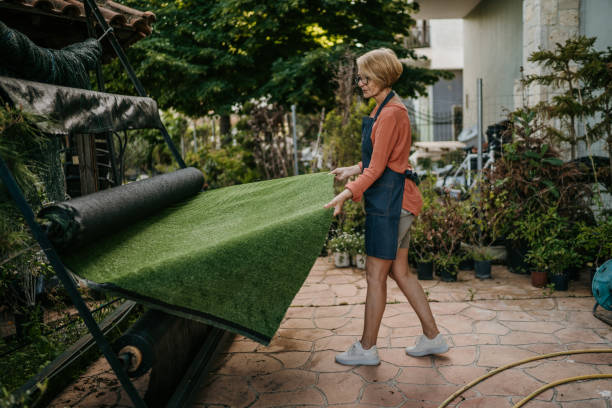 Woman rolling out artificial grass carpet stock photo