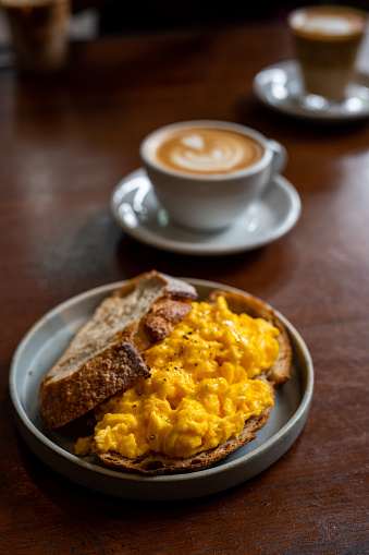 Fluffy and Buttery Scrambled Eggs on Toast with a cup of hot coffee. Daily breakfast.