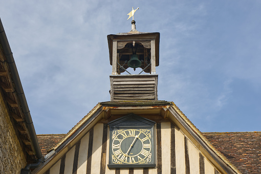 Old building roof with clock, bell and weathervane