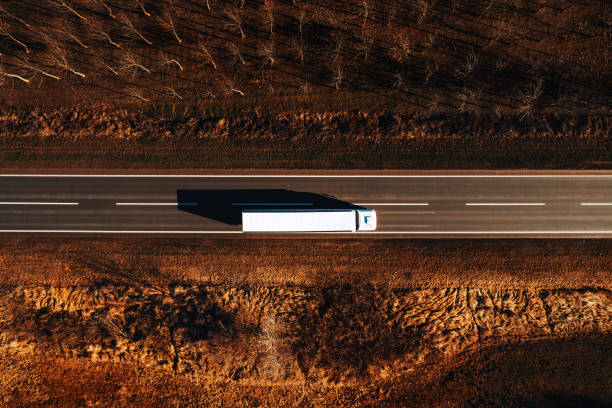 Freight transportation and logistics from above, drone photography of truck on the road Freight transportation and logistics from above, drone photography of truck on the road through plain countryside landscape drone point of view road stock pictures, royalty-free photos & images
