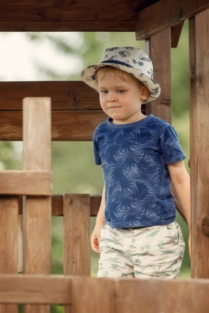 A little boy in a blue shirt on a wooden outdoor playground. stock photo