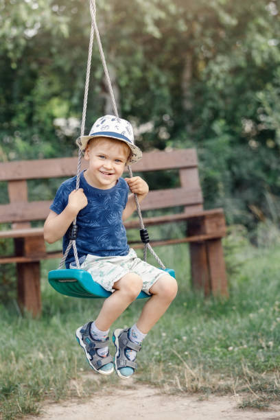 istock Smiling boy swinging on a rope at a playground 1405413692