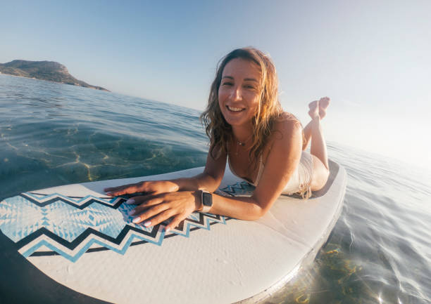 istock Smiling woman sun tanning on paddle board 1405414075