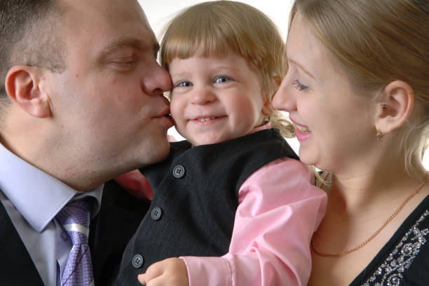 Caucasian family portrait: a little boy puts a hat on his father's head