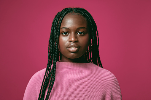 Studio portrait of beautiful serious African teenager against pink background