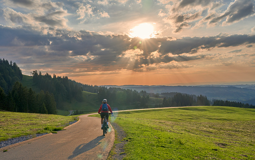 active woman riding her electric mountain bike at sunset in the Allgaeu mountains above Steibis, Bavaria, Germany