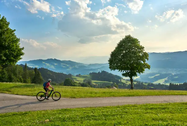 active woman riding her electric mountain bike in the Bregenz Forest mountains near Sulzberg, Vorarlberg, Austria