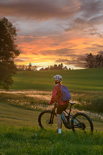 active woman riding her electric mountain bike at sunset in the Bregenz Forest mountains near Sulzberg, Vorarlberg, Austria