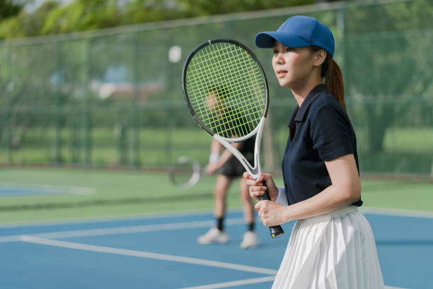 pareja joven asiática jugando al tenis en una cancha de tenis al aire libre en un día soleado y brillante. - torneo de tenis fotografías e imágenes de stock