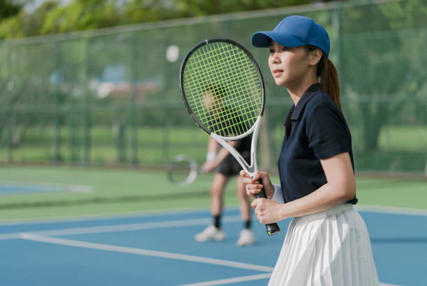 jeune couple asiatique jouant au tennis sur un court de tennis extérieur par une belle journée ensoleillée. - tournoi de tennis photos et images de collection