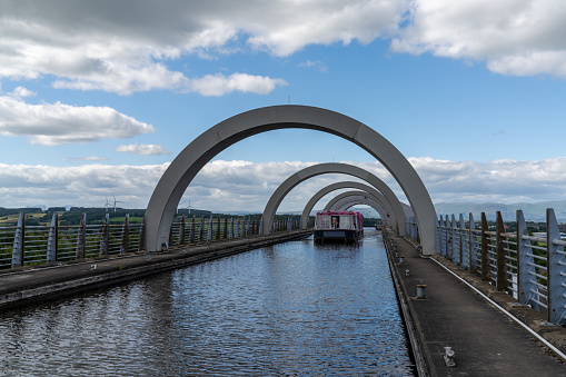 Falkirk, United Kingdom - 19 June, 2022: view of a tourist boat cruise on the Union Canal after leaving. The Falkirk Wheel hydraulic boat lift