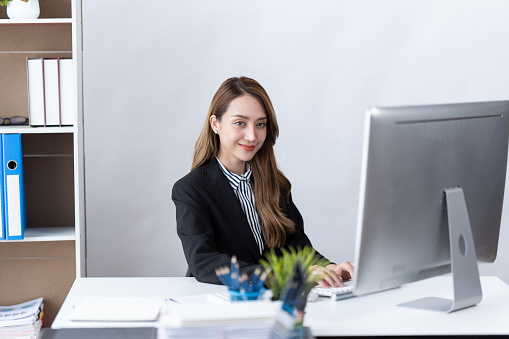 Portrait of Young Asian businesswoman is happy to work at the modern office using a laptop computer. business employee freelance online marketing e-commerce telemarketing concept.