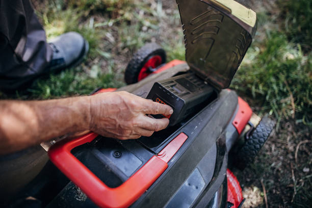 Senior man testing battery in electric cordless lawn mower